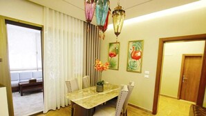 A dining area with a marble table, chairs, and a vase of flowers. There are two paintings on the wall and a door to the right. - Aley Maison des Couleurs - Artistic home in Aley's heart (Alay)