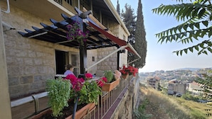 A stone building with a balcony adorned with potted plants and flowers. - Aley Maison des Couleurs - Artistic home in Aley's heart (Alay)