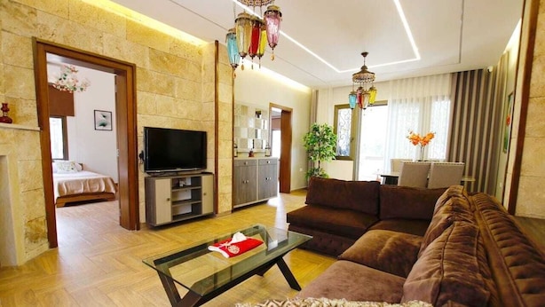 A modern living room with a brown sofa, a glass coffee table, a flat-screen TV, and a stone wall. - Aley Maison des Couleurs - Artistic home in Aley's heart (Alay)
