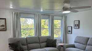 Un saló modern amb un sofà gris, una taula petita i un ventilador de sostre.