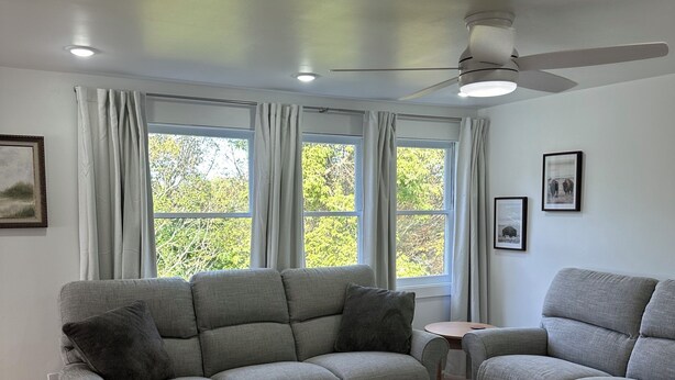 Un salon moderne avec un canapé gris, une petite table et un ventilateur de plafond.