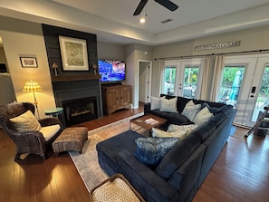 A living room with a fireplace, a sofa set, a television, and a view of the outdoors. - The Chick-Inn: Monthly Discounts, Groups, Parking! (Southport)