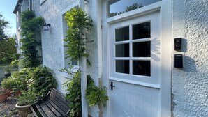 A white door with a window, a bench, and potted plants. - Historic Woodland Getaway, Perfect for Cosy Gatherings - v family-friendly (Kilwinning)