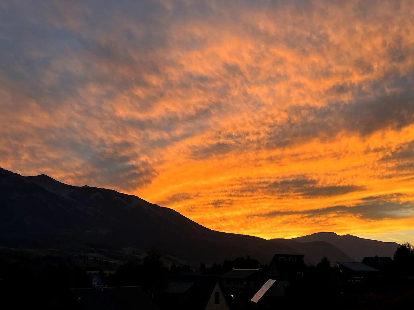 Un atardecer sobre un paisaje montañoso con un pueblo en primer plano.