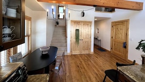A kitchen with a wooden ceiling, a dining table with chairs, and a staircase leading to an upper level. - Mountain Views, Hot Tub & Breathtaking Stars: A Slice of Paradise (Crested Butte)