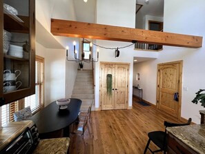 A kitchen with a wooden ceiling, a dining table with chairs, and a staircase leading to an upper level. - Mountain Views, Hot Tub & Breathtaking Stars: A Slice of Paradise (Crested Butte)