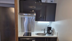 Una cocina compacta equipada con lavavajillas, cafetera y refrigerador de acero inoxidable.