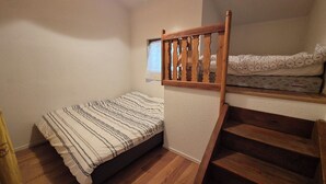 Un dormitorio pequeño y acogedor con una cama individual, una escalera de madera y una ventana con vistas.