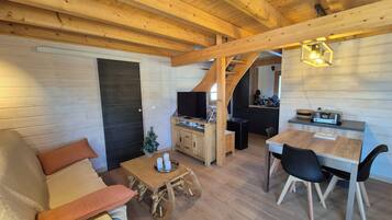 Un intérieur chaleureux en bois, avec un canapé, une table basse, une table à manger et un coin cuisine.