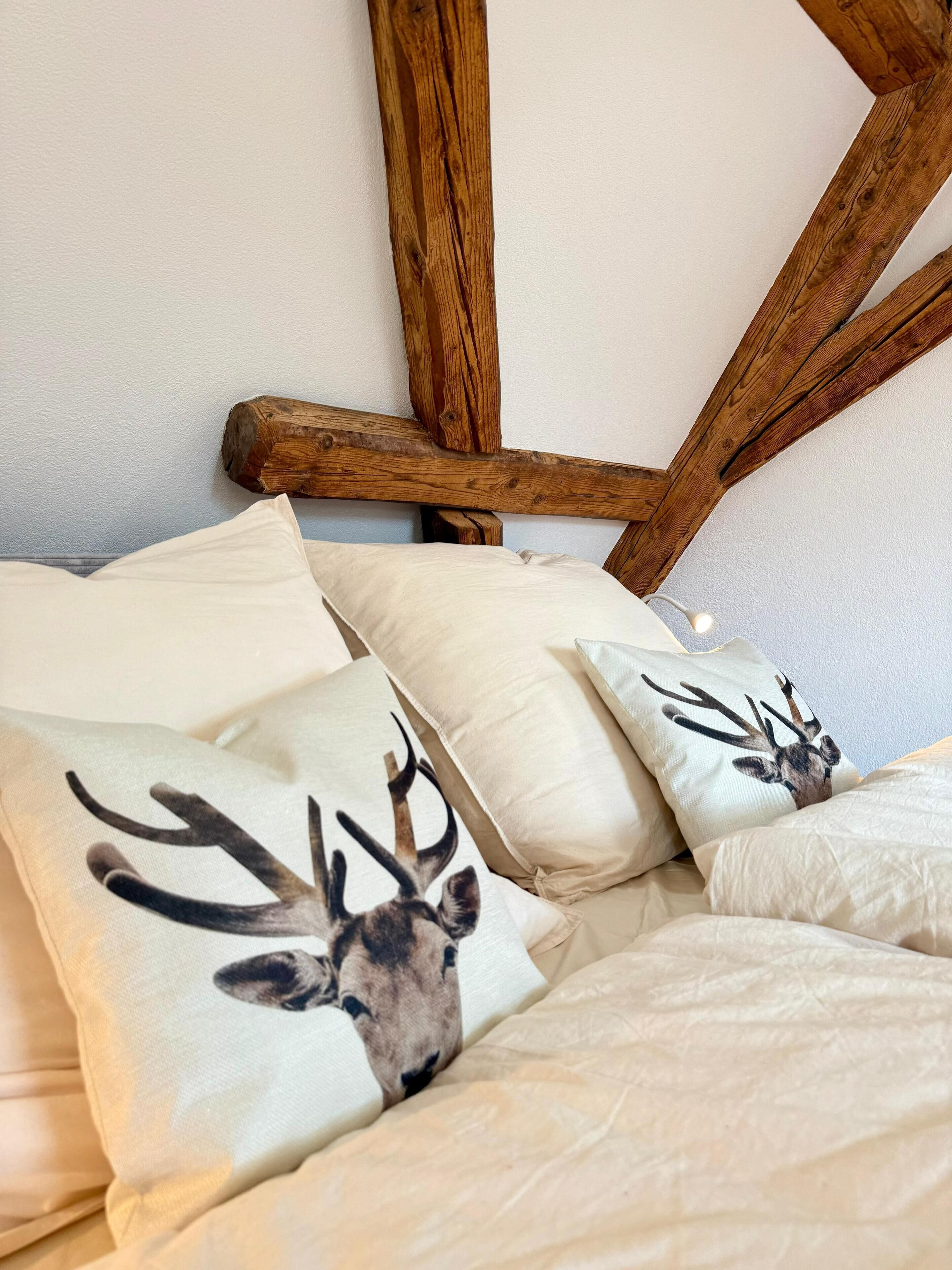 Una cama con ropa de cama y almohadas con estampado de ciervo.