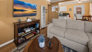 A living room with a sofa, a coffee table with a plant, a bookshelf, and a painting on the wall. - Chipmunk House (Big Bear Lake)