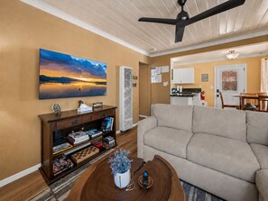 A living room with a sofa, a coffee table with a plant, a bookshelf, and a painting on the wall. - Chipmunk House (Big Bear Lake)