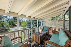 A covered outdoor seating area with wicker furniture and a fire feature. - Chipmunk House (Big Bear Lake)