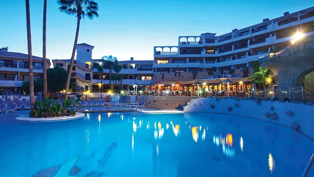 A resort with a large pool, multiple balconies, and outdoor seating areas.