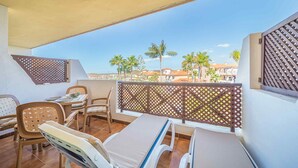 A balcony with a table, chairs, and a lounge chair.