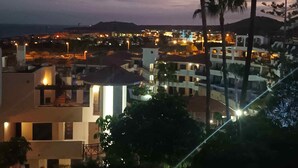 A coastal town at dusk with illuminated buildings and palm trees.