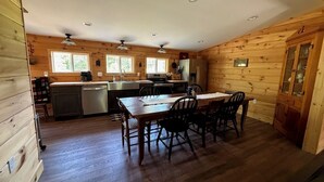 A cabin-style kitchen with a dining table and chairs, wooden walls, and a refrigerator. - Cabin Fever II is a cozy 3-bedroom cabin in the foothills of the Blue Ridge.  (Luray)