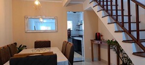 A dining area with a table, chairs, a mirror, and a staircase.