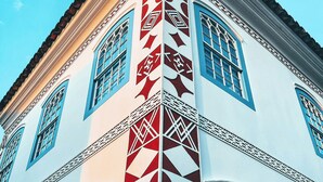 Un bâtiment à la façade blanche et aux encadrements de fenêtres bleus, orné de motifs géométriques et de détails architecturaux traditionnels.