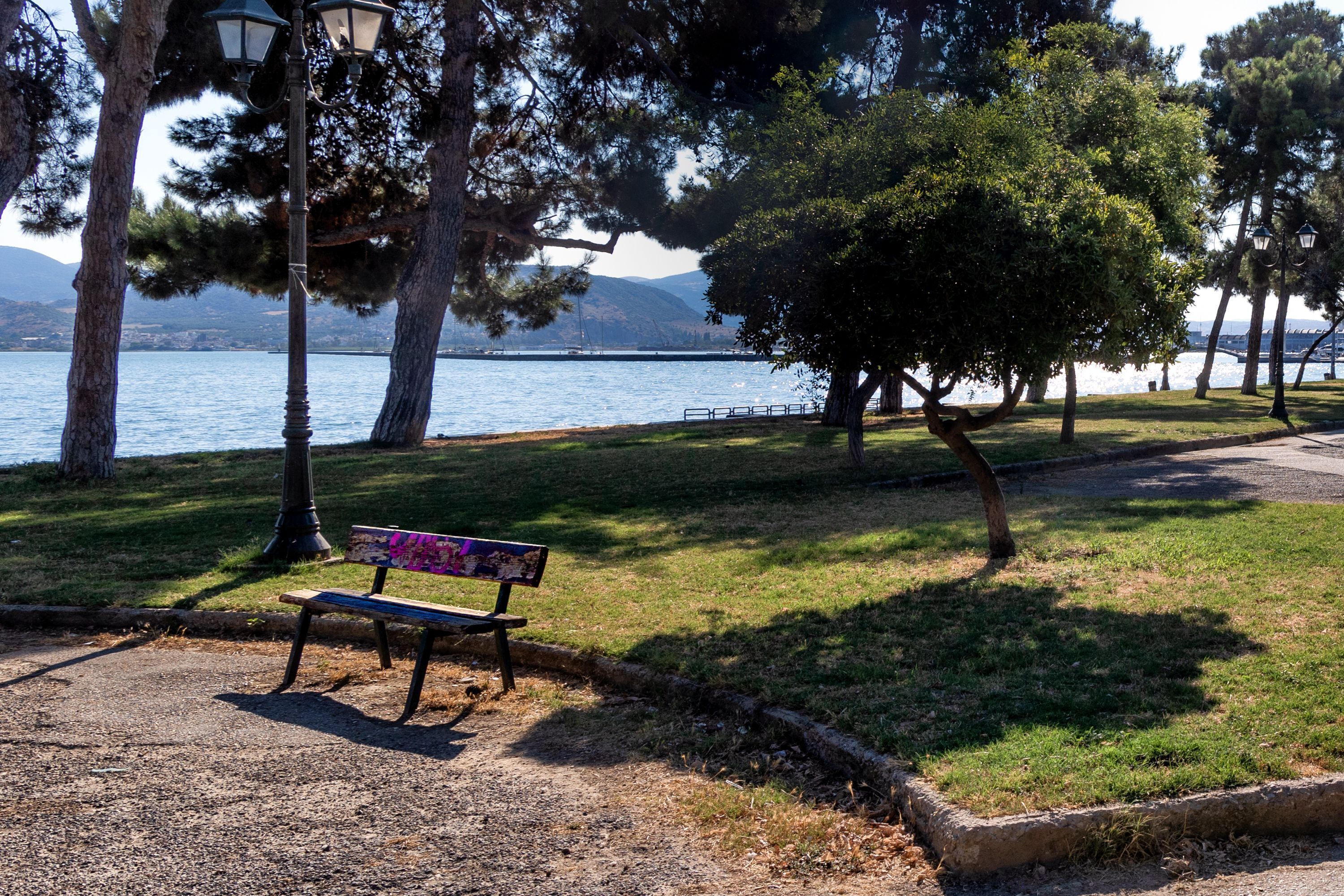 A park bench with a view of a lake and mountains.