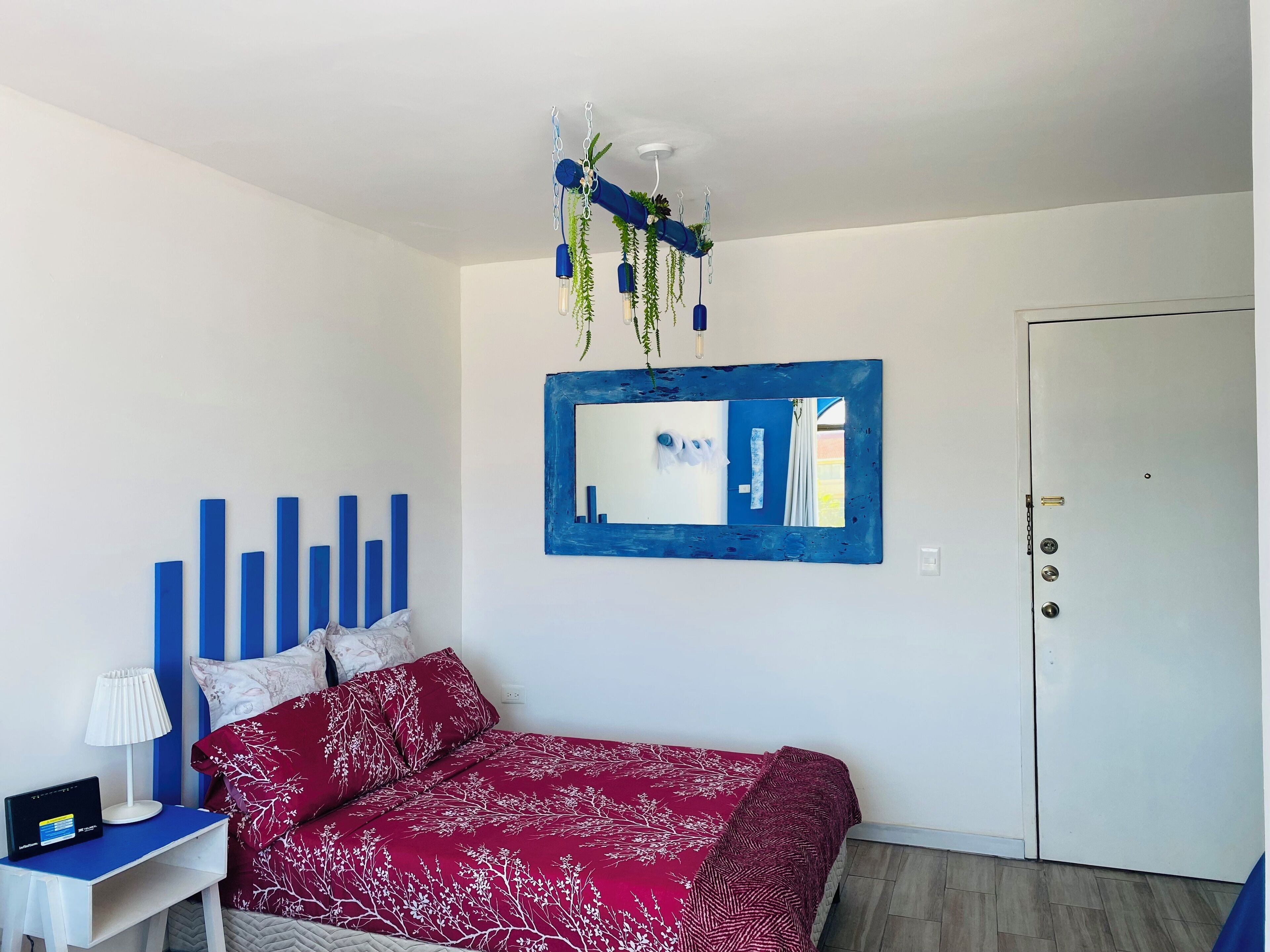 Une chambre à coucher avec un lit, un bureau, une chaise, un miroir et une porte.