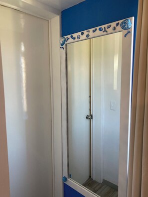 Ein Badezimmer mit Duschabtrennung aus Glas, einer weißen Tür und einer blauen Akzentwand.