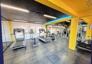 A gym with treadmills, a stationary bike, and weight machines. - tropical apartment (Cancún)