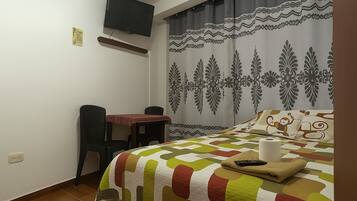 Un dormitorio pequeño y ordenado con cama, escritorio y silla.