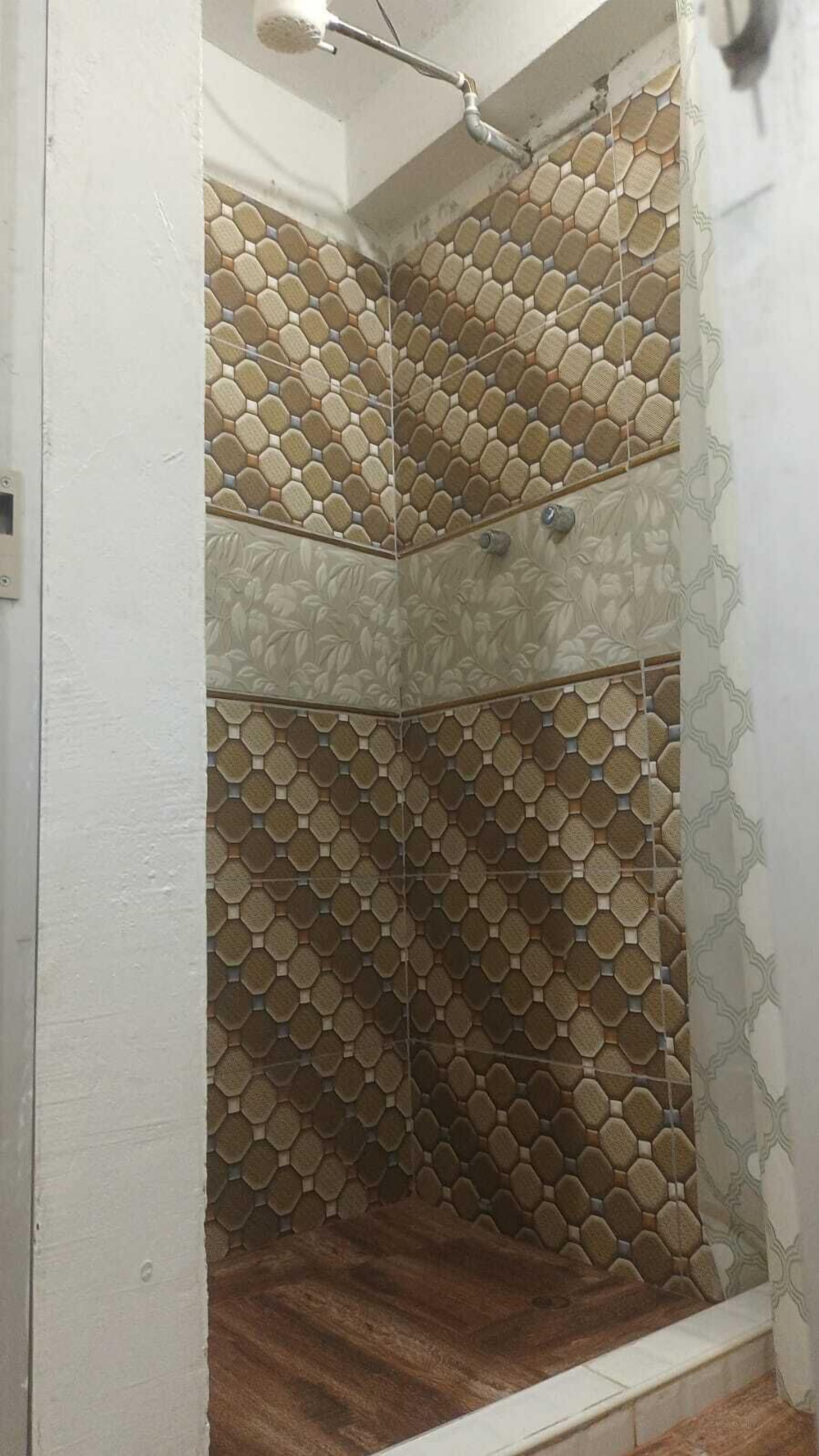 A shower with a hexagonal tile pattern and a wooden floor.