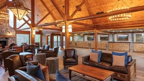 A spacious lobby with wooden beams, leather sofas, and a stone fireplace.