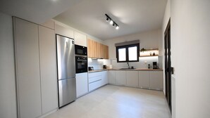 Una cocina moderna con electrodomésticos de acero inoxidable, armarios de madera y un amplio ventanal que proporciona luz natural.