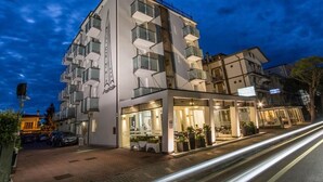 A modern hotel with a white facade, multiple balconies, and a ground-level restaurant. - Carinthia (Lido di Jesolo)