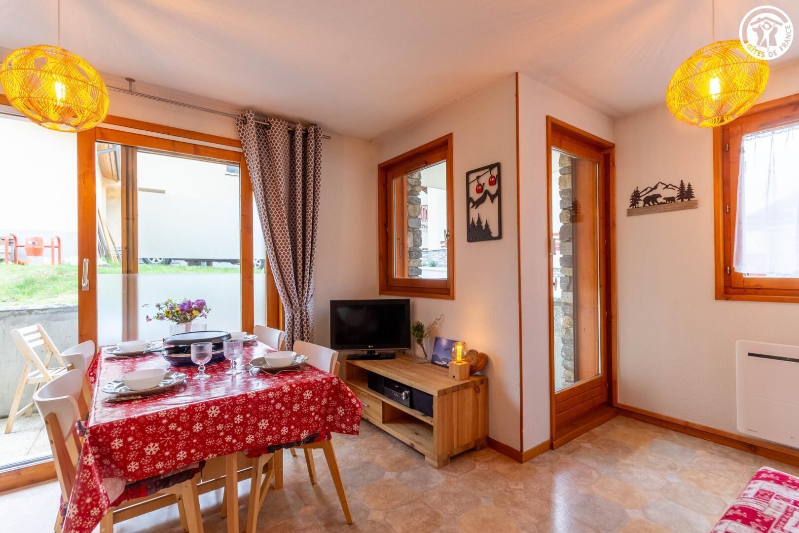 Ett mysigt rum med ett matbord för två personer, en tv och en eldstad i sten.