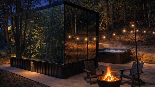 A modern glass structure with a fire pit and seating area, surrounded by trees and a hot tub. - Mirrored Glass Studio · Hot Tub · Nature Views (Laurelville)