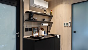 Een moderne keuken met een ingebouwde airconditioning, een koffiezetapparaat en een klein plankje met keukengerei.