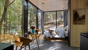 Een moderne slaapkamer met een groot raam, een bed, een tafel met een vaas en een stoel.