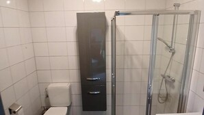 A modern bathroom with a toilet, a glass-enclosed shower, and a vanity with a sink. - "Sur les prés" is a tent set up in a meadow, 100% natural. (Ohey)