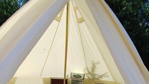 A tent with two beds, a small table, and a refrigerator. - "Sur les prés" is a tent set up in a meadow, 100% natural. (Ohey)