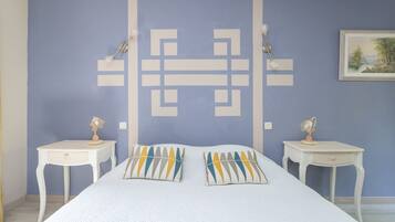 A bedroom with a bed, two bedside tables, and a wall with a geometric pattern.