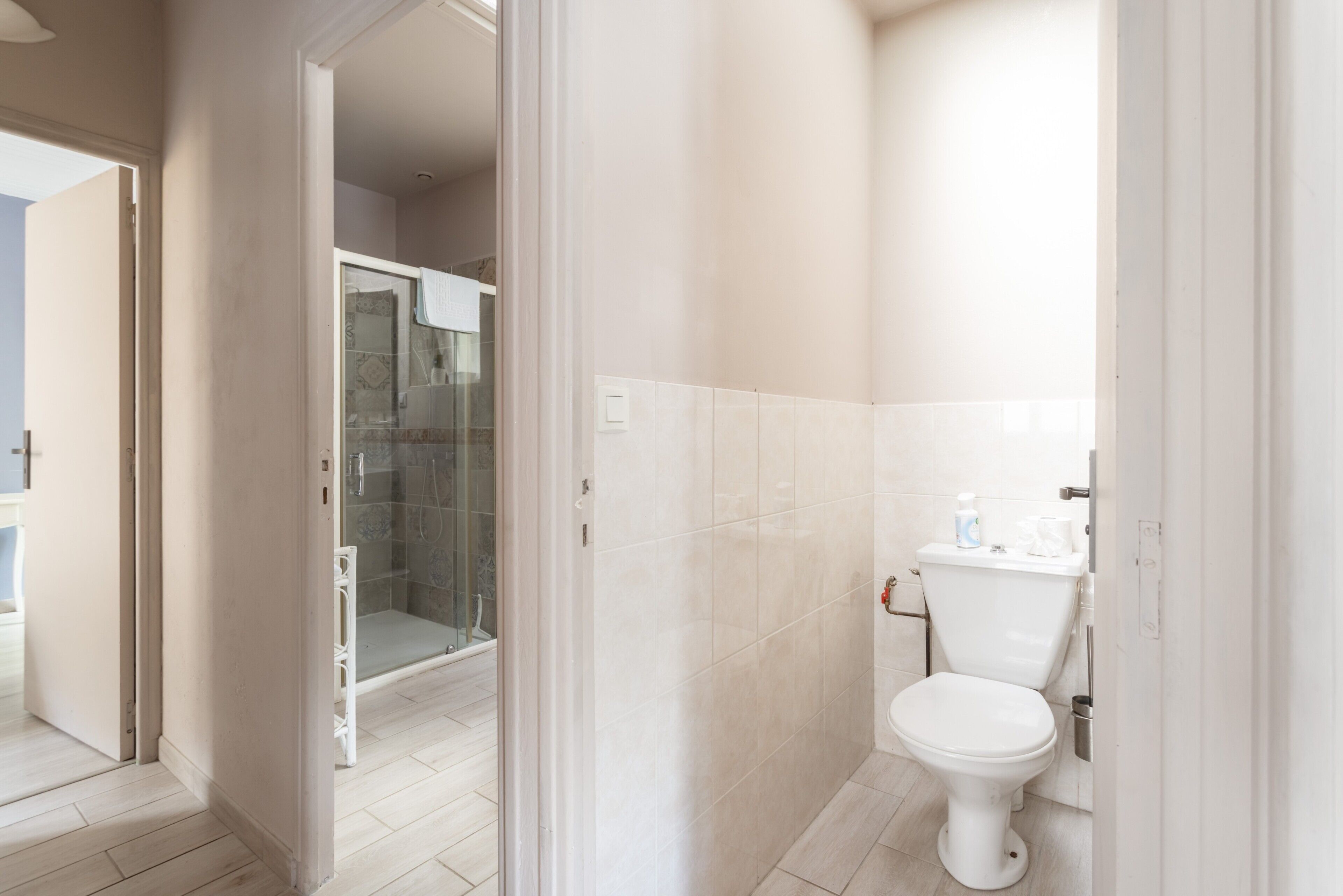 A bathroom with a toilet, a shower, and a glass-enclosed shower area.