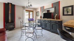 A modern kitchen with a built-in stove, a dining area with a glass table and metal chairs, and a red and black accent wall.