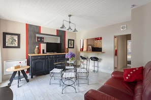 A modern kitchen with a central island, black cabinets, and a red accent wall.