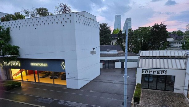 A modern building with a white facade and a Ferrari dealership on the ground floor.