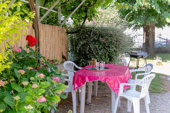 Eine Terrasse mit Tisch, Stühlen, einem Grill und einem Holzzaun.