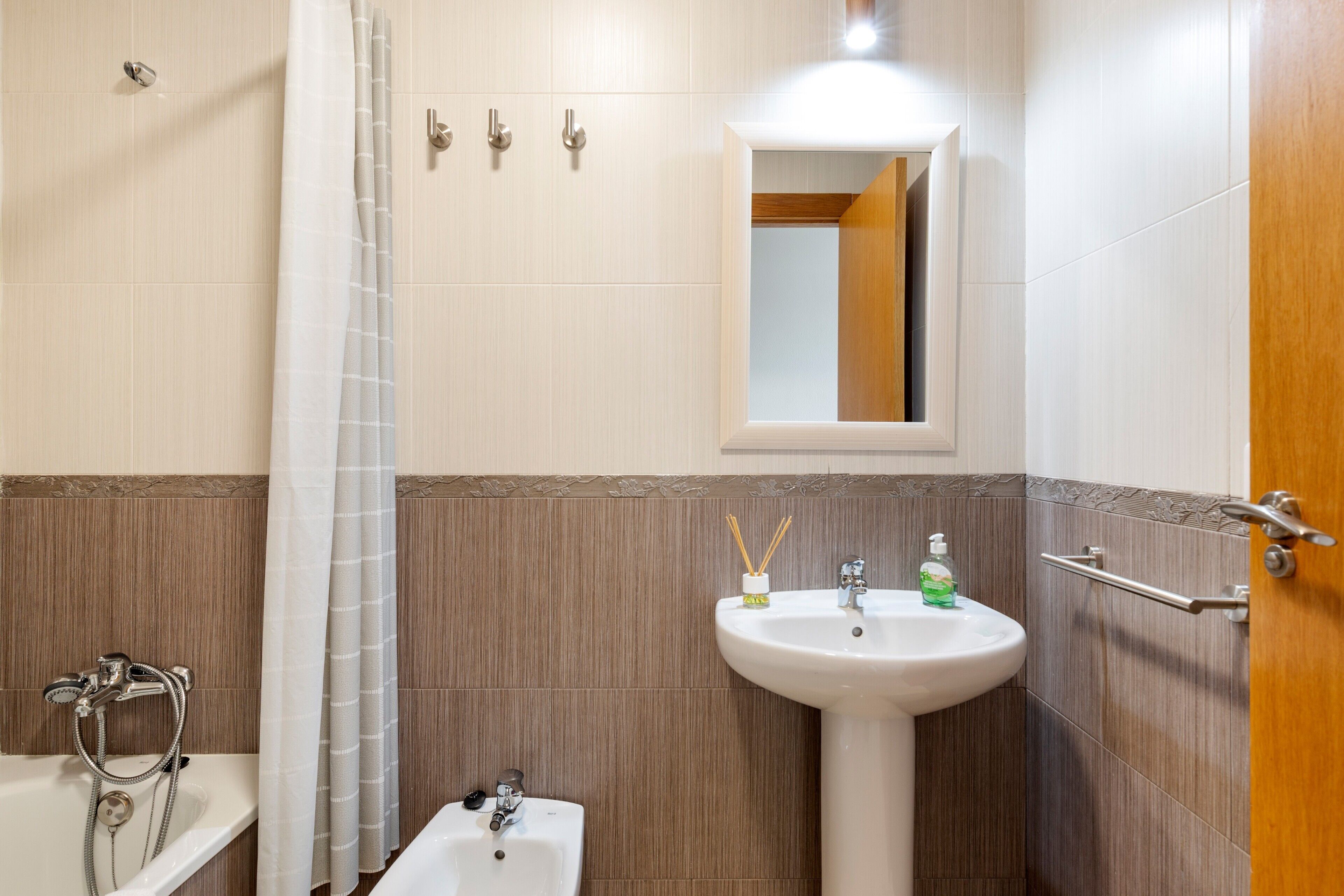 A bathroom with a bathtub, a sink, a mirror, and a shower curtain.