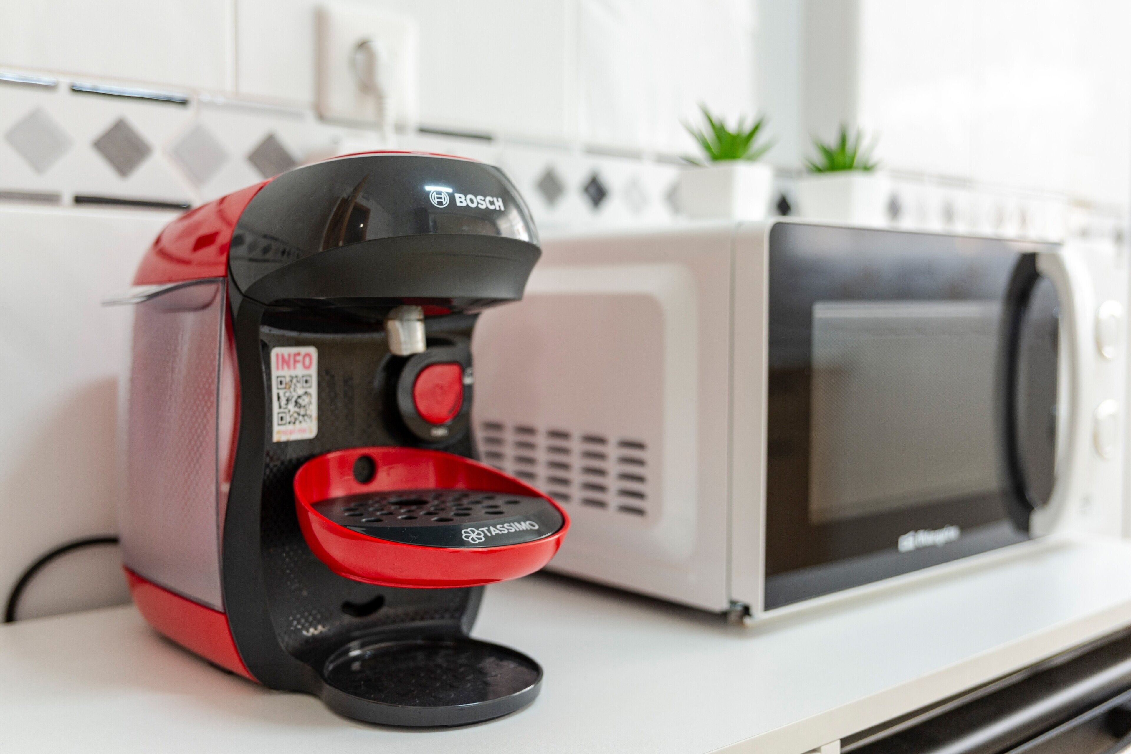 A coffee machine with a red drip tray and a microwave oven.