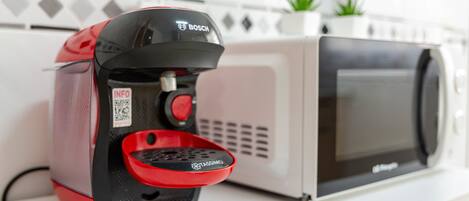 A coffee machine with a red drip tray and a microwave oven.