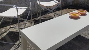 A rooftop terrace with two metal chairs, a white table, and two bowls on the table. - ‘Vista Castello - Otranto’ Apartment with Sea View, Wi-Fi, and Air Conditioning (Otranto)
