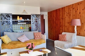 A living room with a sofa, a coffee table, a lamp, and a wooden wall.