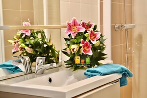 A bathroom with a sink, mirror, and shower.